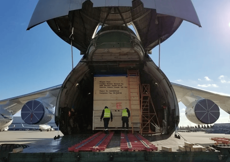 Cargo aircraft with open bay door and workers loading a crate