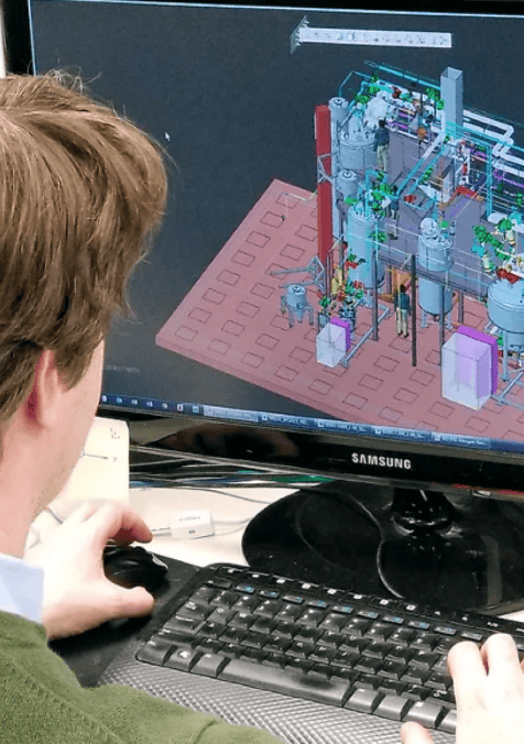 Person working on a computer with CAD software displaying a 3D model.